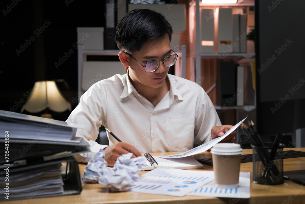 Young businessman working overtime on a desk at night.. Young businessman working overtime on a desk at night..