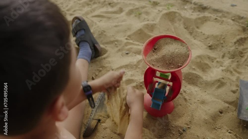 Unrecognizable little boy spending fun time playing in the sand. Concept of outdoor freeplay for kid development and social skill for childhood. Family time photo