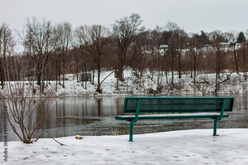 View of bench overlooking pond in winter