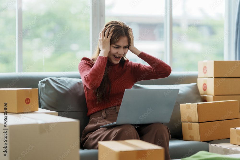 Young woman working at small business ecommerce using laptop stressed and frustrated surprised and angry face. Small online business owner woman stressed headache with parcel box at home. Young woman working at small business ecommerce using laptop stressed and frustrated surprised and angry face. Small online business owner woman stressed headache with parcel box at home.