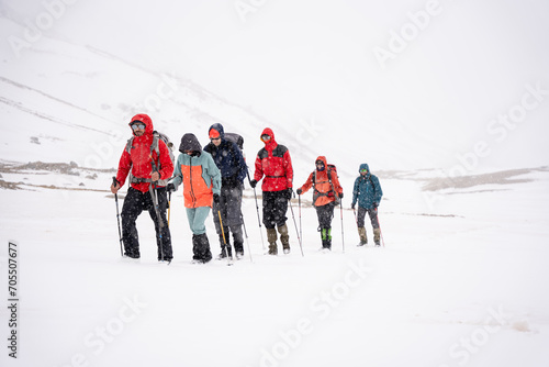 A group of people walking on the snowy mountains with their snowshoes on. Climbing the icy mountains photo