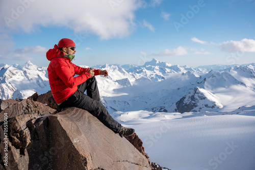 Tourist sits and rests while climbing in winter mountains.