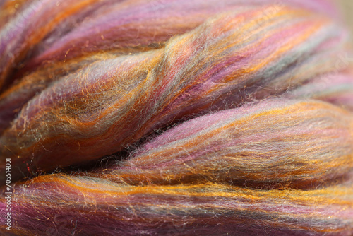 Closeup detail of colourful sheep wool merino, alpaca and silk fibres in a roving pleat, ready for spinning on traditional spinning wheel.	 photo