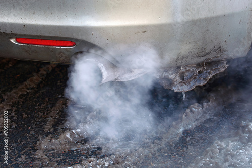 Smoke from car pipe exhaust closeup, exhaust smoke. Car exhaust pipe smoking in cold weather. Engine warming up at idle in winter season. .