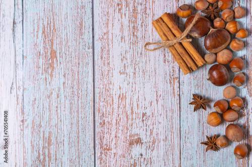 Hestnuts, star anise, cinnamon and cobnuts on a light blue wooden background with copyspace photo