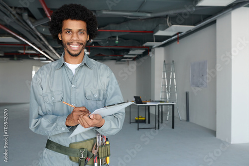 Portrait of smiling foreman taking notes in document and smiling at camera