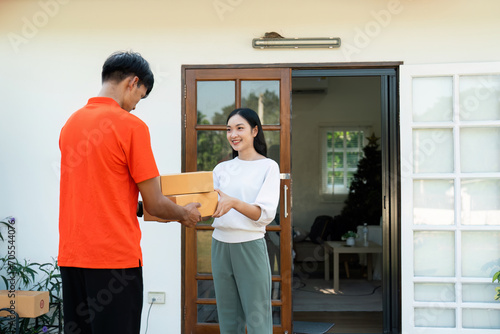 Young Asian cute girl receiving boxes from postman at the door. Delivery concept © itchaznong
