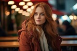Beautiful young redhead woman in winter coat at the cafe.