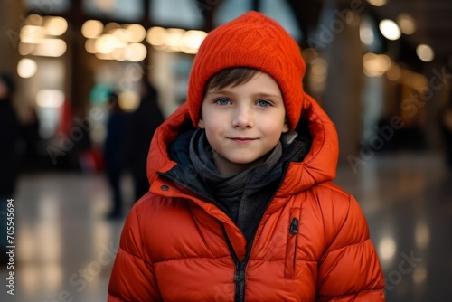 Portrait of a cute little boy in a red hat and coat in the city.