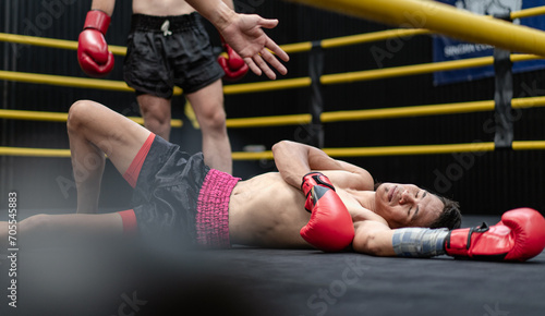 Konstfotografi Unconscious Asian boxer lay on floor referee countdown knockout in fighting ring at fitness gym
