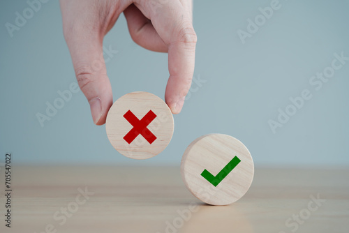 Hand pick red wrong or reject icon on wood cube and check mark symbol stand on table for true or false changing mindset or way of adapting to change leader and transform quiz answer and poll concept.