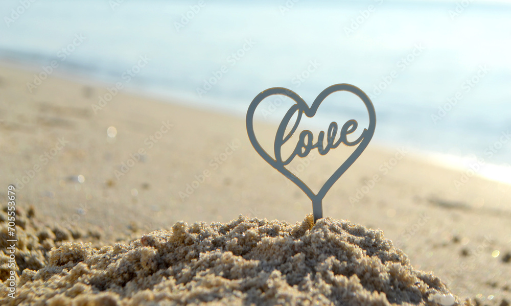 Plastic stick in shape of heart and word Love in sand on beach seashore on sunny summer day close-up. Figures in shape of heart word Love on background of sea waves. Love relationship romance concept Plastic stick in shape of heart and word Love in sand on beach seashore on sunny summer day close-up. Figures in shape of heart word Love on background of sea waves. Love relationship romance concept