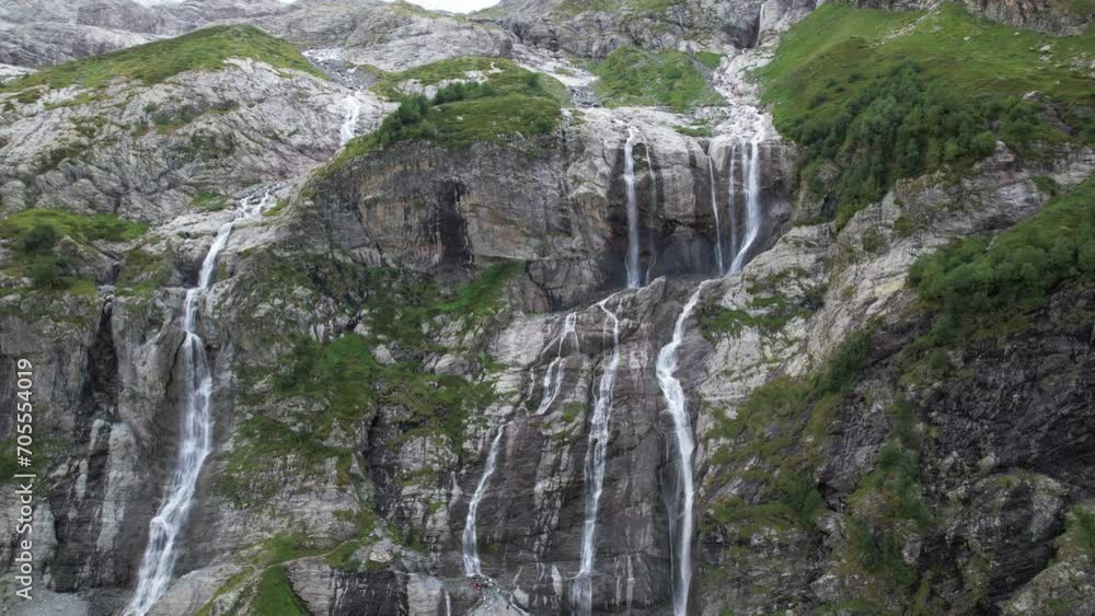 A gorgeous waterfall flows down in many streams from a mountain glacier A gorgeous waterfall flows down in many streams from a mountain glacier