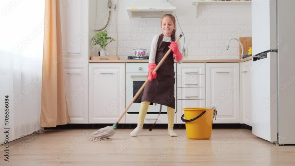 Little girl in household gloves washing floor with modern mop and water container near kitchen set Home wet cleaning using brush as microphone having fun while helping her mother with household chores Little girl in household gloves washing floor with modern mop and water container near kitchen set Home wet cleaning using brush as microphone having fun while helping her mother with household chores