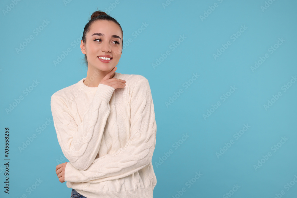 Beautiful young woman in stylish warm sweater on light blue background, space for text Beautiful young woman in stylish warm sweater on light blue background, space for text