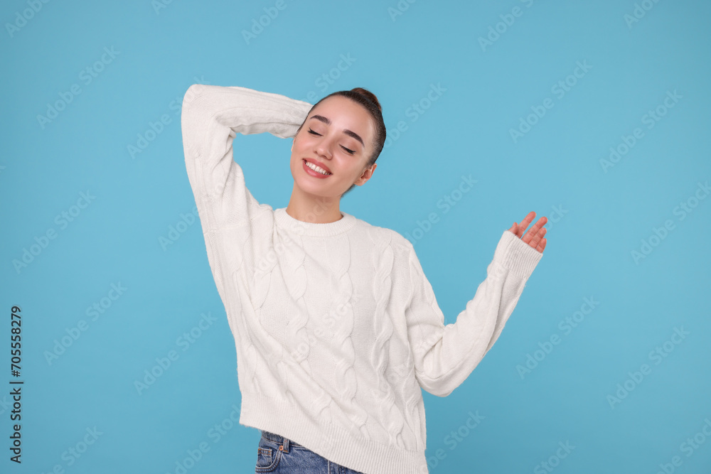 Beautiful young woman in stylish warm sweater on light blue background