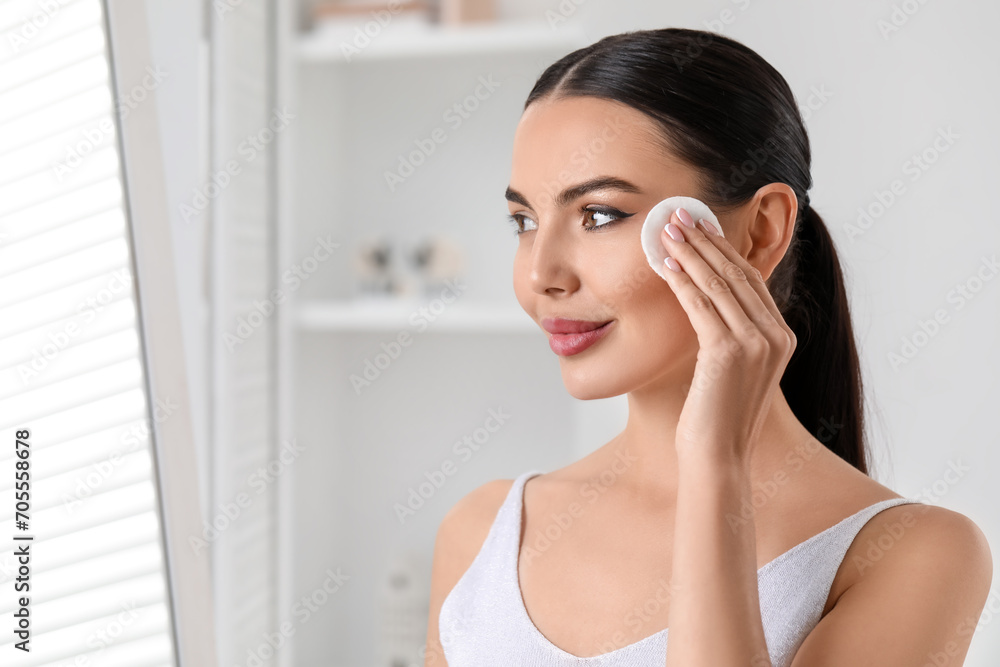 Beautiful woman removing makeup with cotton pad indoors, space for text Beautiful woman removing makeup with cotton pad indoors, space for text