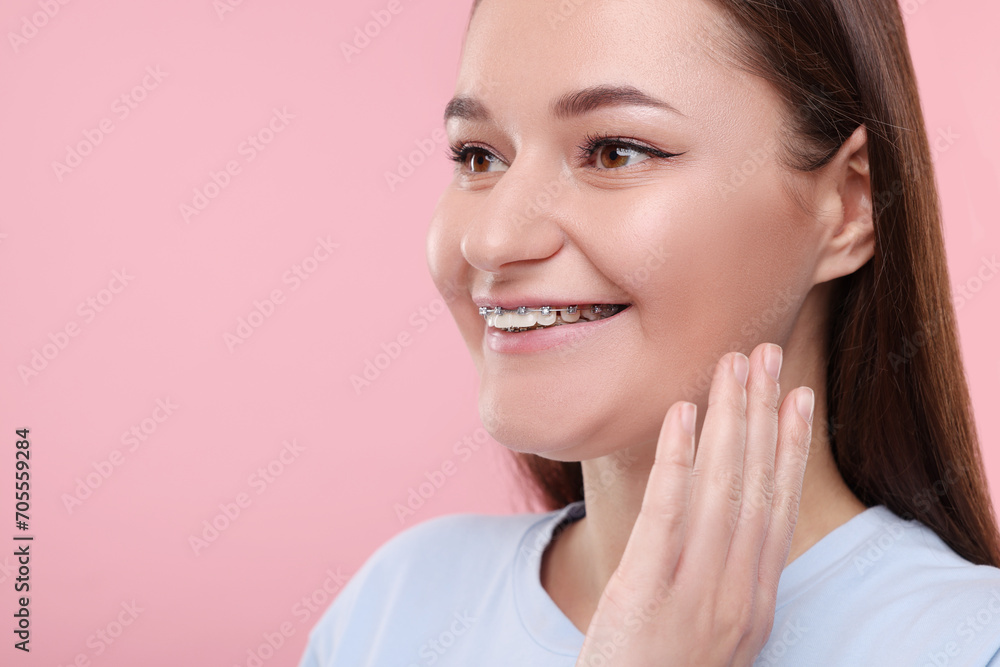 Smiling woman with dental braces on pink background. Space for text Smiling woman with dental braces on pink background. Space for text
