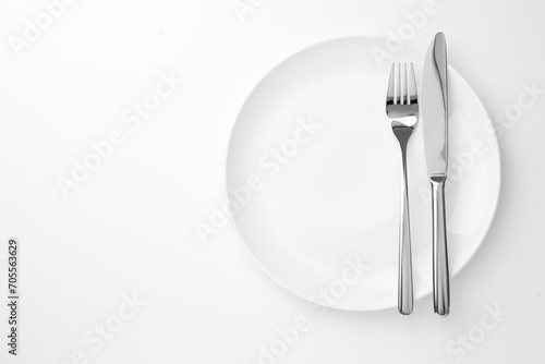 Plate  fork and knife on white background  top view. Space for text