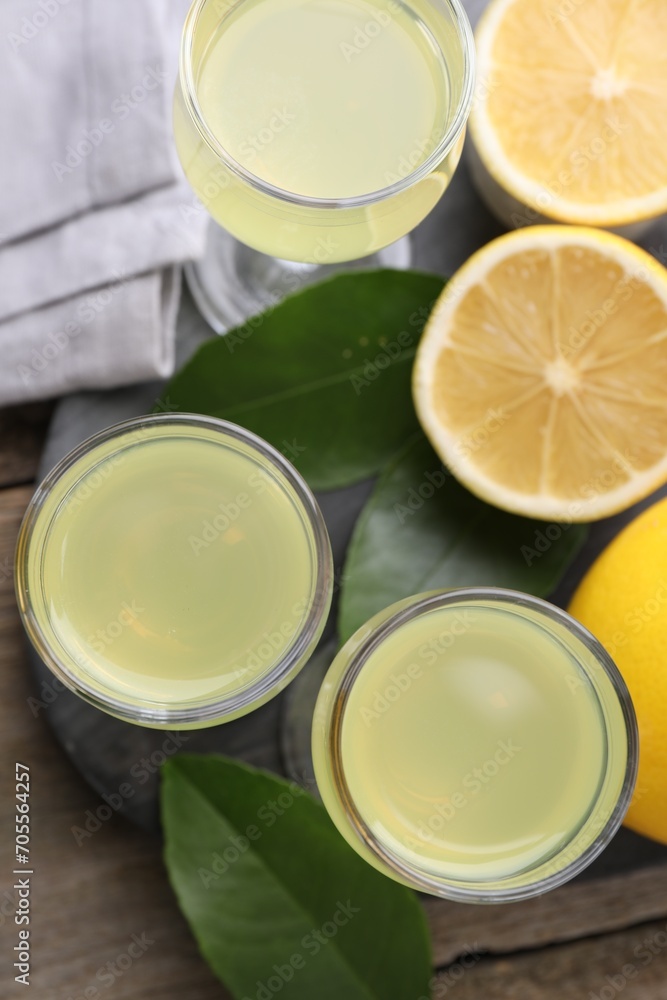 Tasty limoncello liqueur, lemons and green leaves on table, top view Tasty limoncello liqueur, lemons and green leaves on table, top view