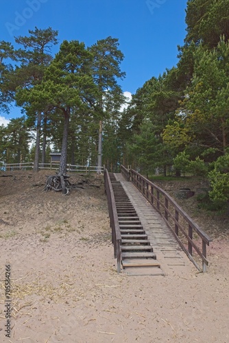 Fototapeta Naklejka Na Ścianę i Meble -  Wooden stairs to sandy beach in autumn with clouds in sky, Lappohja, Finland.