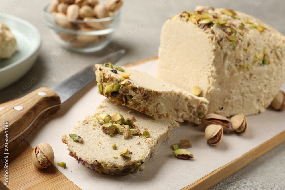 Tasty halva with pistachios and knife on grey table, closeup