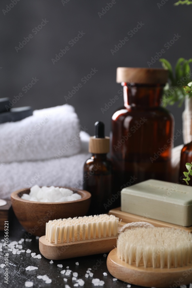 Spa composition. Brushes, soap bar and sea salt on black table