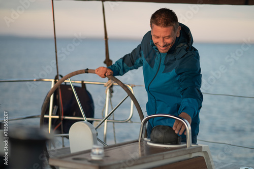 Mature man standing near the steering whell on the yacht