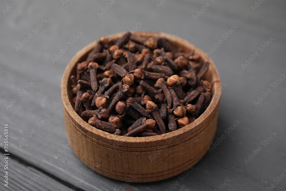 Aromatic cloves in bowl on grey wooden table, closeup Aromatic cloves in bowl on grey wooden table, closeup