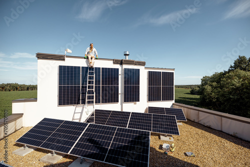 Rooftop of a private house with solar power station on it, man sitting on a top and enjoys his property. Concept of renewable energy and sustainable lifestyle