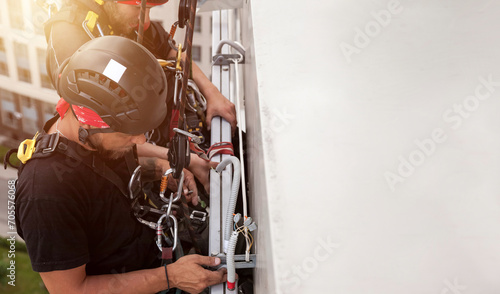 Industrial mountaineering worker hangs over residential building photo