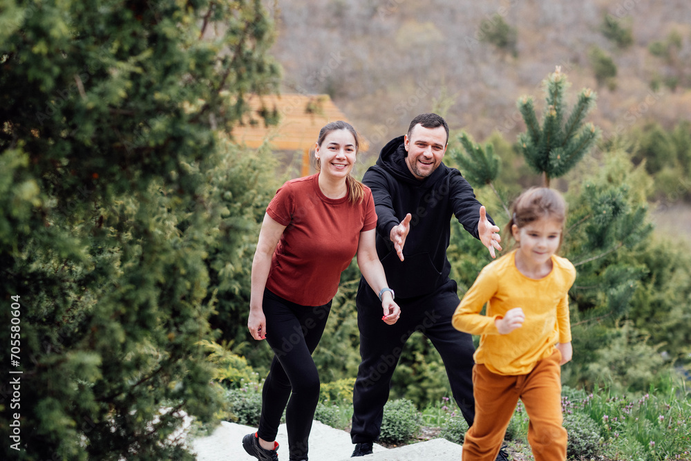 Happy family jogging in the summertime. Smiling young couple with their cute daughter doing sport