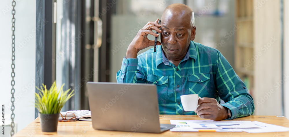 Portrait of Senior African man sitting on laptop at the home office and having a phone conversation with the insurance company. - obrazy, fototapety, plakaty 