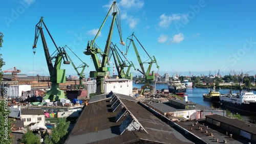 Shipyard cranes aerial view. Establishing shot of shipyard by the Baltic sea in Gdansk, Poland, Europe. Industrial seaside scene, ships in the harbor and dry dock. photo