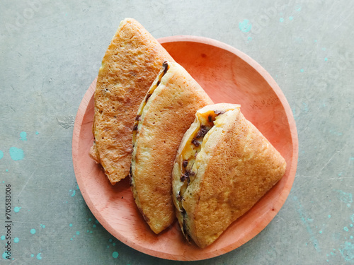 pieces of martabak filled with chocolate sprinkles on a wooden plate on a gray background. martabak, traditional Indonesian sweet snack. soft bread filled with chocolate, for tea time or celebrition photo