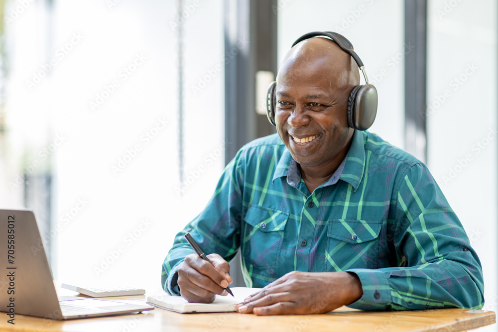 Portrait of happy African American senior man 60 years old wearing headphones, enjoying working at home office. Portrait of happy African American senior man 60 years old wearing headphones, enjoying working at home office.