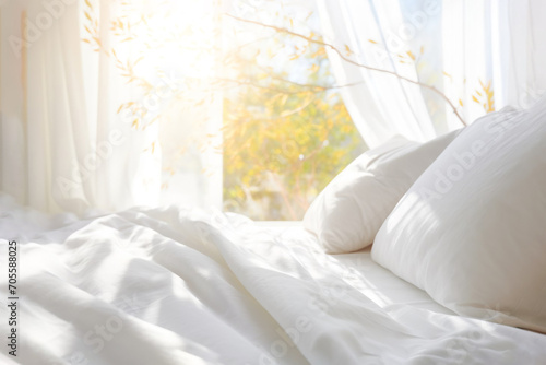 White bed linen. cozy bedroom with window with curtains is flooded with sunny morning light photo