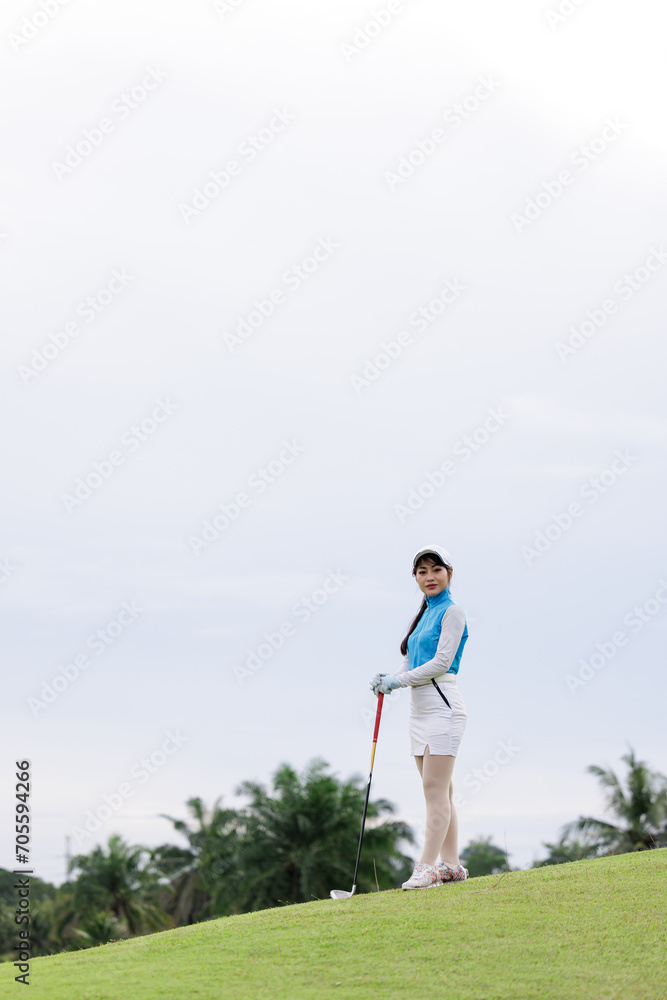 Portrait of young asian female golfer holding the golf club at the course