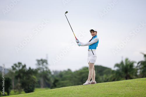 Portrait of young asian female golfer holding the golf club at the course