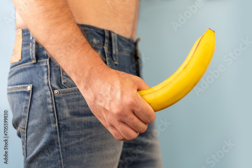 man's hand holds a banana on the background of a fly, close-up. Potency concept, impotence, male strength, pills to improve potency. copy space photo