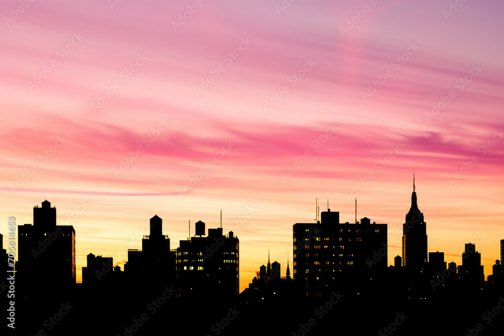 A stunning city skyline silhouette against a vibrant pink and orange sunset sky.