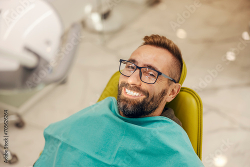 Portrait of a patient sitting at dentist office in chair with perfect smile.