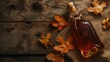 Maple syrup bottle surrounded by autumn leaves on a wooden table