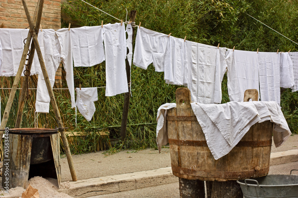 Ancient vat of laundry, brazier and old underwear and sheets hanging to dry. Laundry hung out, clothesline with ancient linen Ancient vat of laundry, brazier and old underwear and sheets hanging to dry. Laundry hung out, clothesline with ancient linen