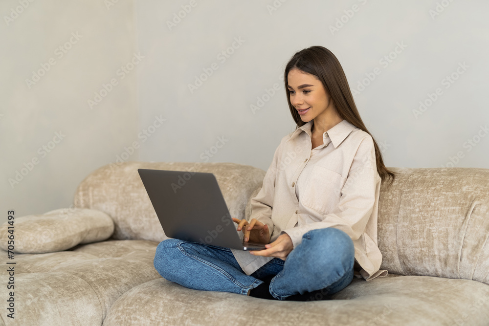 Young Woman using a laptop while relaxing on the couch Young Woman using a laptop while relaxing on the couch