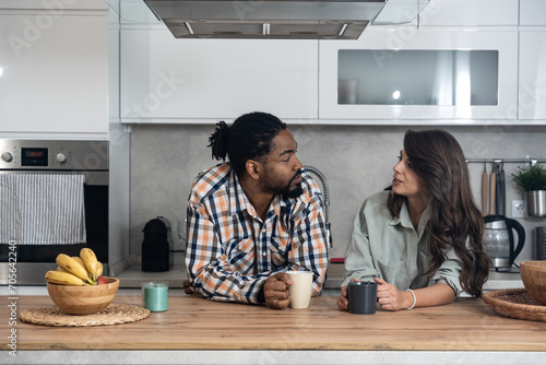 Business colleagues talk during lunch break in office kitchen. Woman communicates with workmate hold coffee cups enjoy conversation, discuss work or personal. Good relations at work concept photo