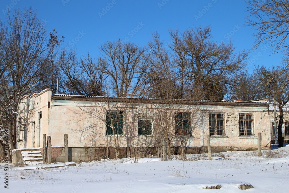A white building with a fence and trees in the snow A white building with a fence and trees in the snow