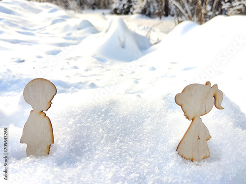 Wooden toys of boy and girl on white snow. Couple in love on Valentine's Day in February. Love in a cold world. Card, background