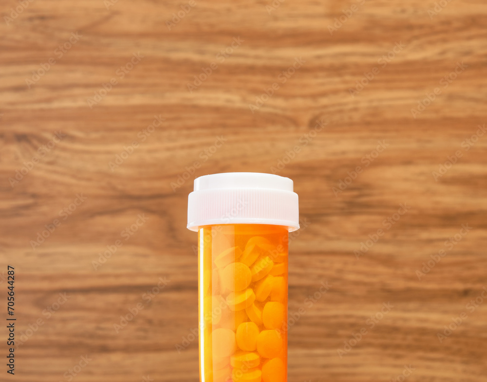 Orange medical jar with pills on a wooden background. Disease treatment. Orange medical jar with pills on a wooden background. Disease treatment.