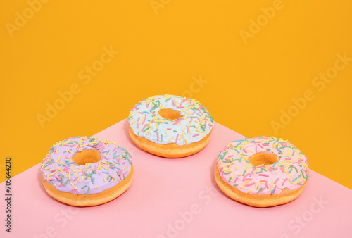 Three sweet, fresh donuts with bright sprinkles on the table. Sweet collection.